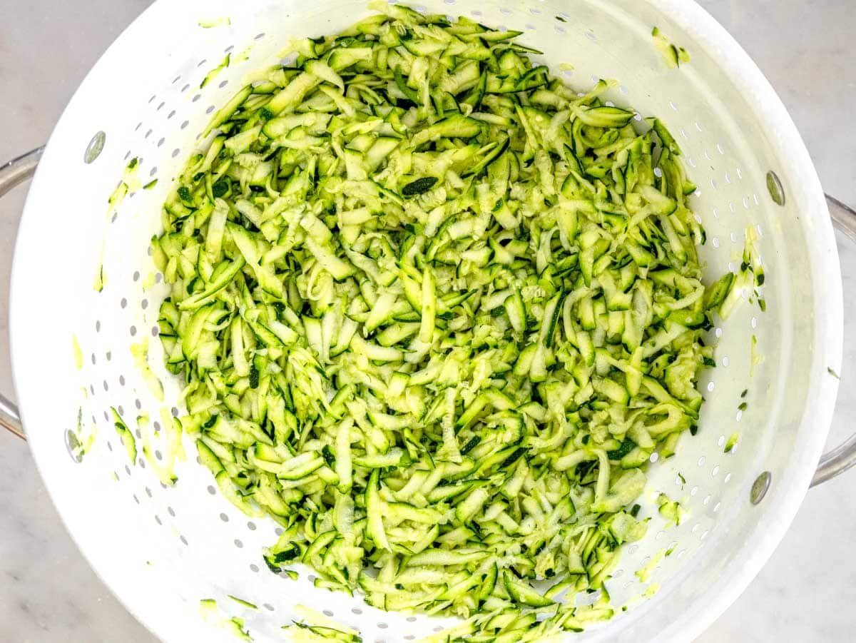grated zucchini draining in a colander