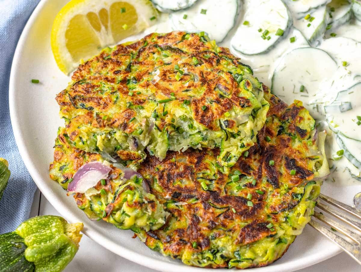 Zucchini fritters served with creamy cucumber salad on a plate