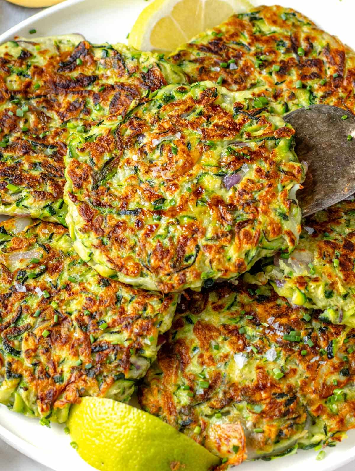 Zucchini fritters with lemon wedges and a silver spatula