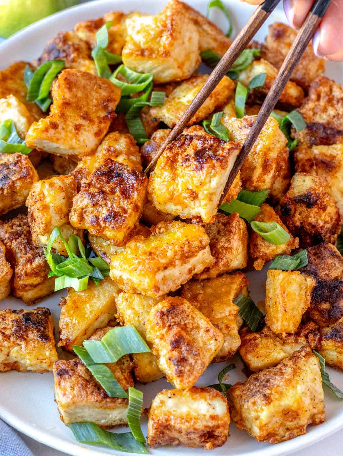 fried tofu with chopsticks and scallions