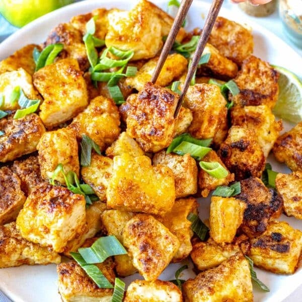 fried tofu served on a white plate with scallions