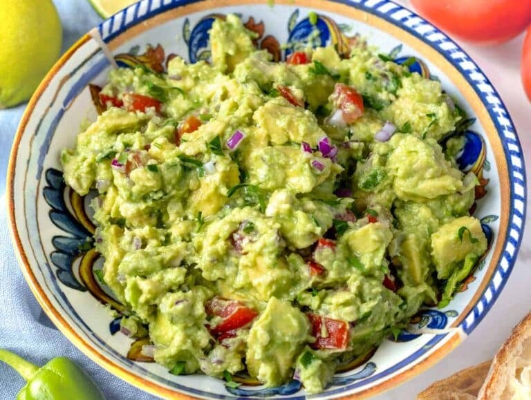 guacamole with tomatoes and jalapenos in a bowl