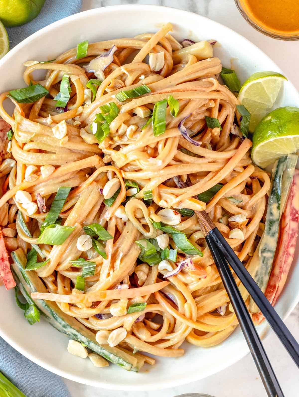 peanut noodles in a white bowl with chopsticks