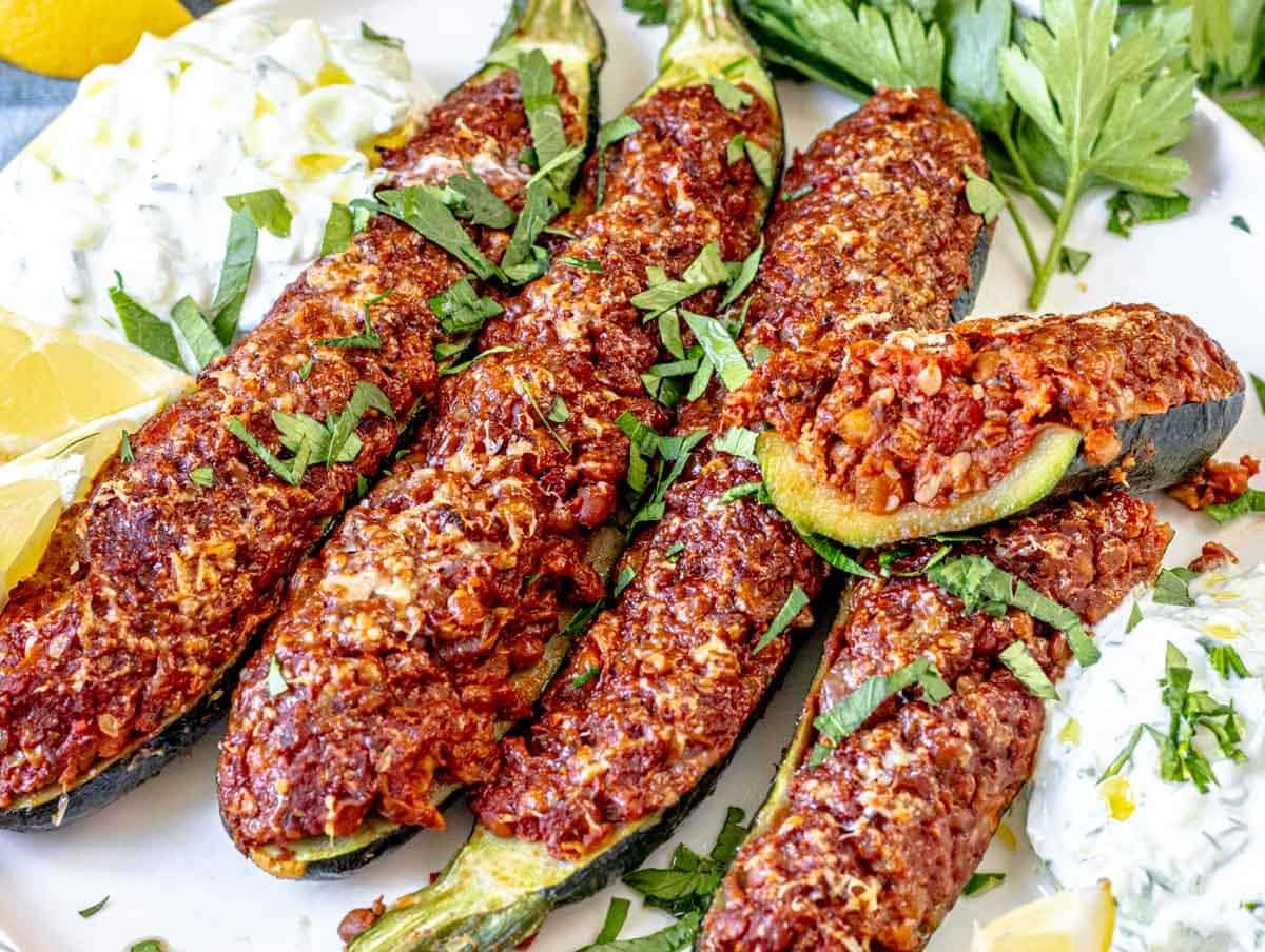 zucchini boats on a plate with tzatziki and parsley