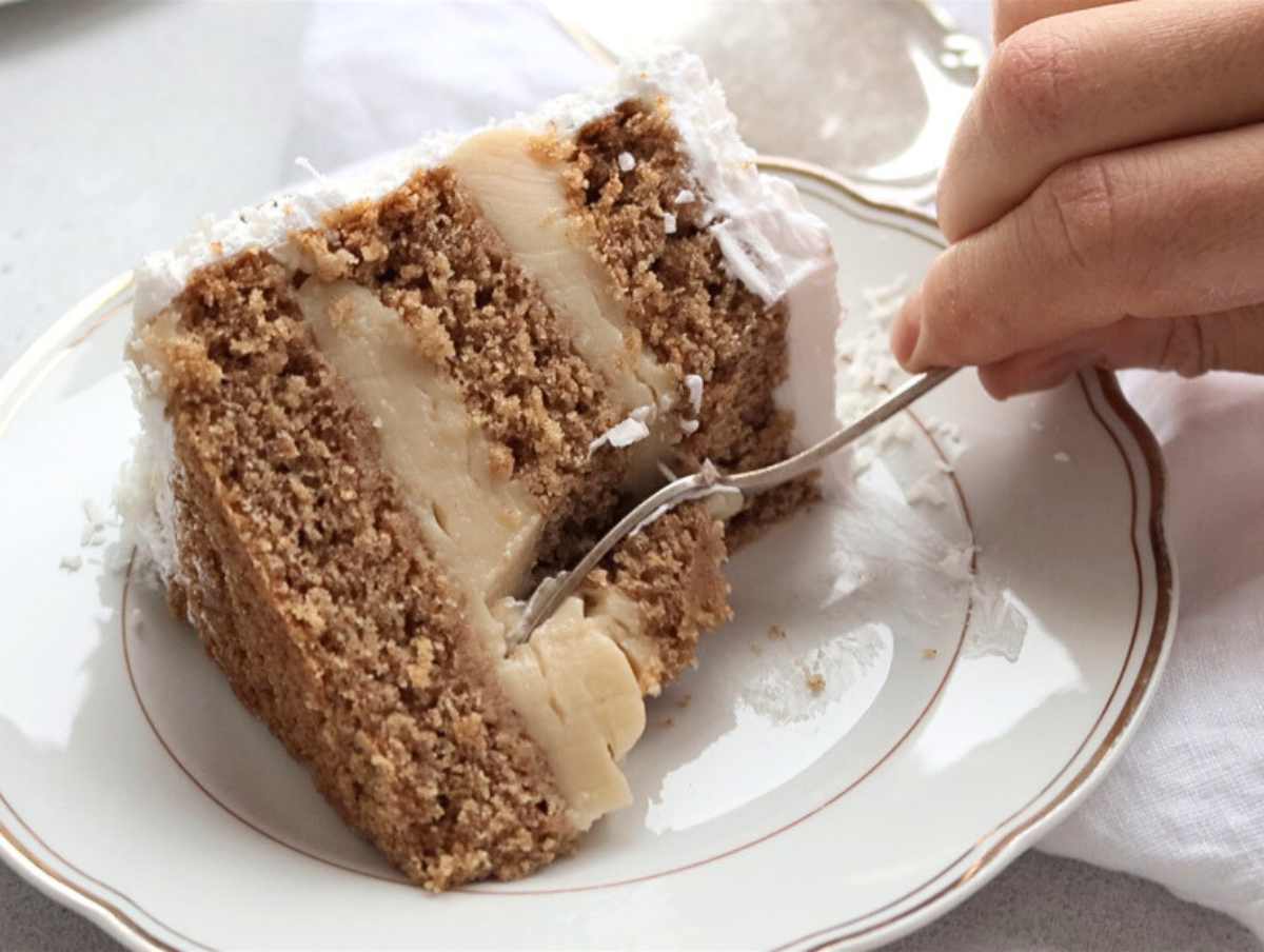 vegan coconut cake and hand holding a fork