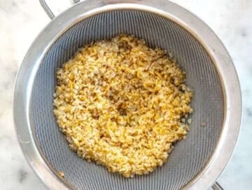 Bulgur cooked and drained in a sift.