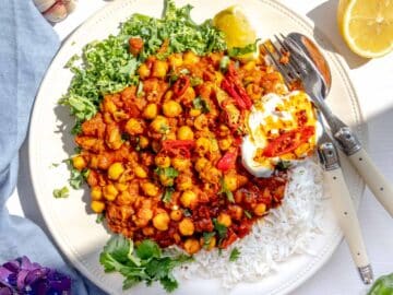 Chana masala served on a plate with kale, yogurt, and chili oil