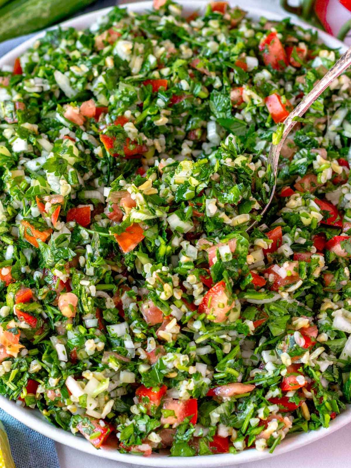 Close-up of a fresh tabouli (tabbouleh) recipe showing finely chopped parsley, bulgur, tomatoes, and mint in vibrant detail.