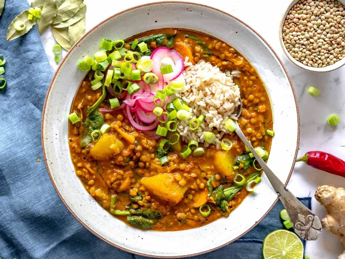 curry lentil soup topped with rice, pickled onions, and scallions