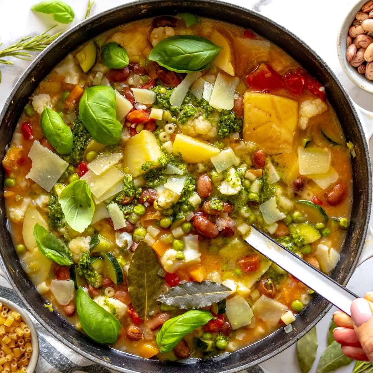 Minestrone soup in a dutch oven with a white ladle