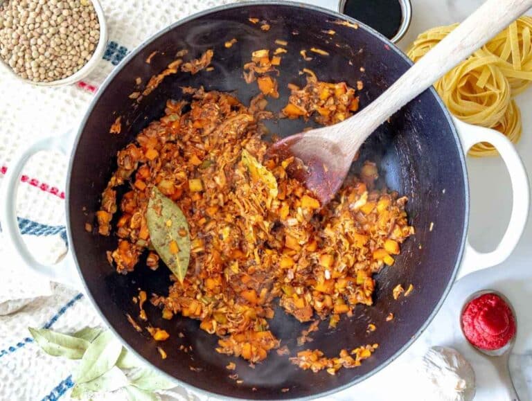 Step 2 Grated mushrooms, tomato paste, rosemary, and bay leaves cooking with the softened vegetables in the pot.
