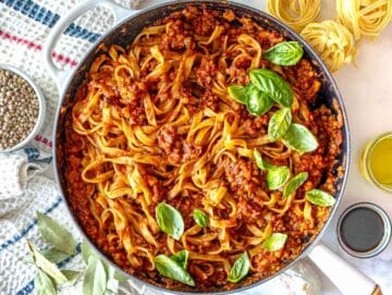 Step 4 Cooked pasta being tossed with lentil Bolognese and a splash of pasta water until evenly coated in sauce.