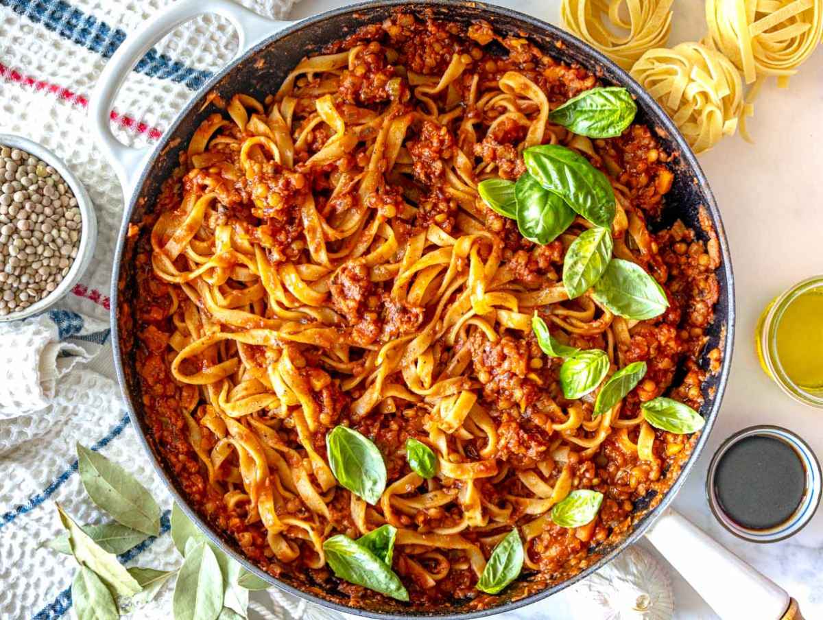 Step 4 Cooked pasta being tossed with lentil Bolognese and a splash of pasta water until evenly coated in sauce.