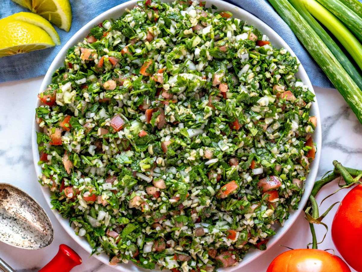 Tabouli (tabbouleh) salad served in lettuce cups and with pita on the side, perfect for a plant-based side dish.