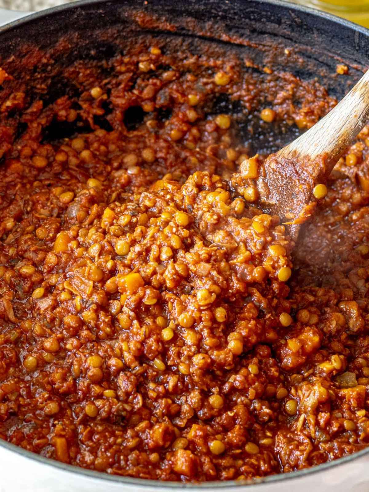 Thick lentil Bolognese with tender lentils, mushrooms, and finely chopped vegetables in a large pot.