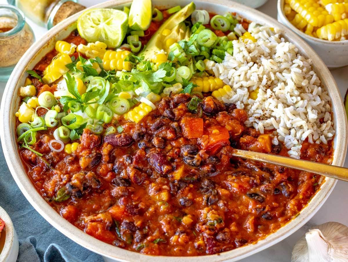 Vegetarian chili with brown rice, corn on the cob and lime