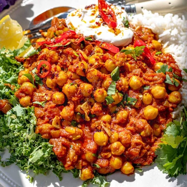 chana masala with kale and a dollop of yogurt on a plate