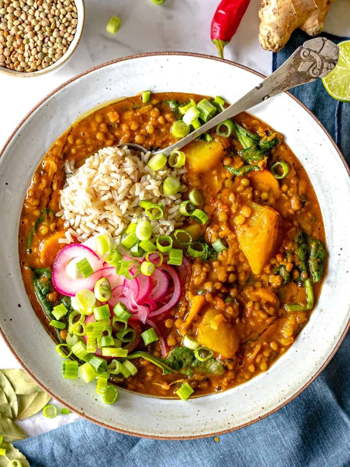 curry lentil soup in a bowl with rice and onions