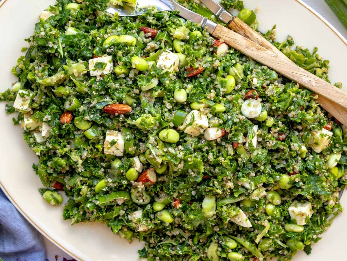 kale quinoa salad on a white platter with a blue cloth