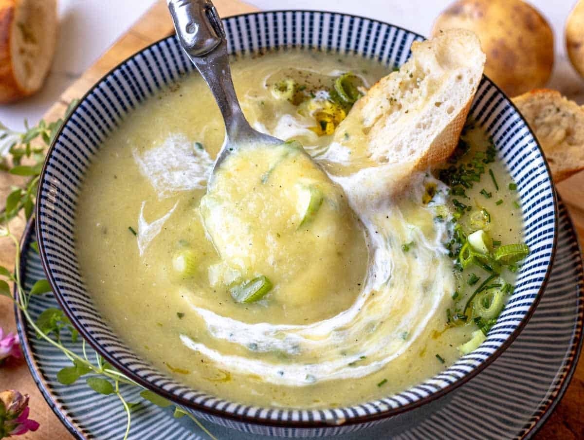 a spoonful of creamy potato leek soup with crusty bread