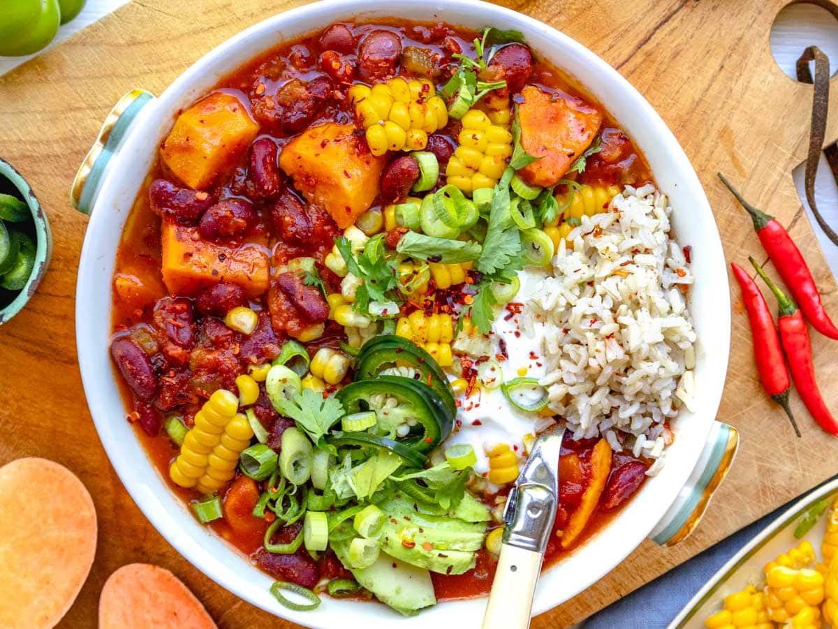 sweet potato chili in a bowl topped with corn, lime, and cilantro