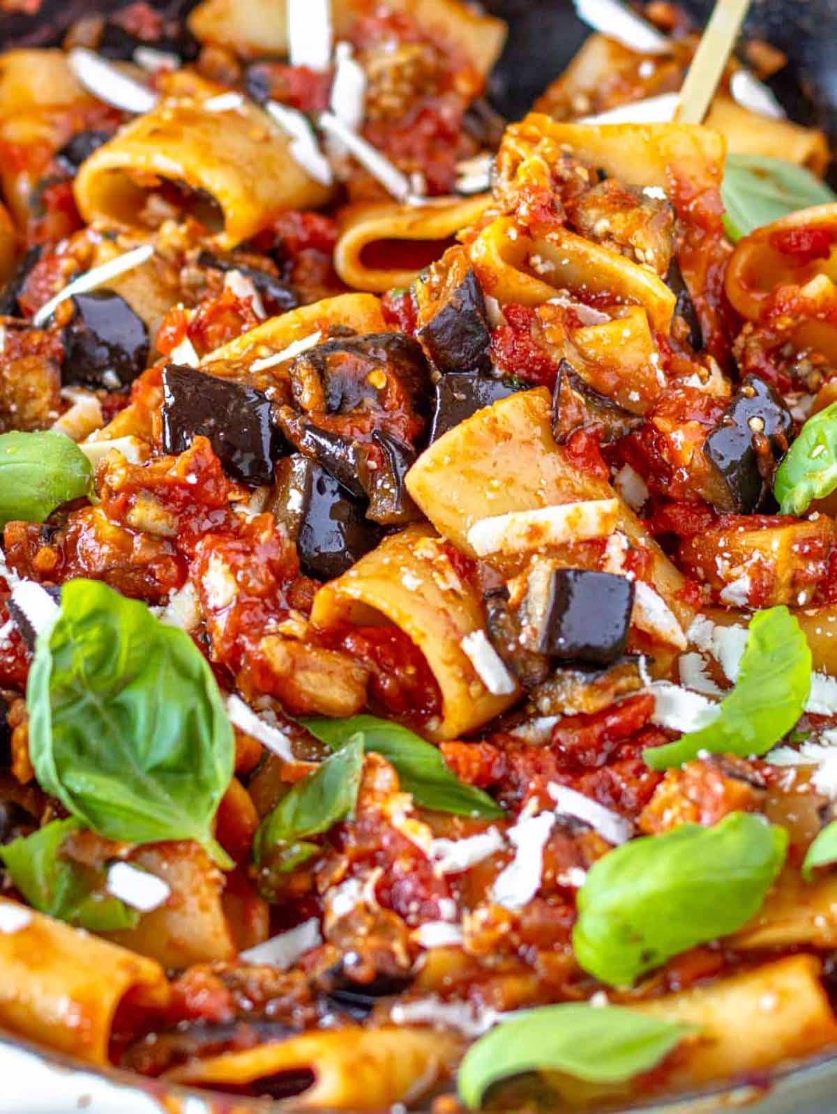 Close up of pasta alla Norma with ricotta salata and tender roasted eggplant pieces.