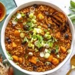 Lentil stew with scallions in a bowl and a slice of bread