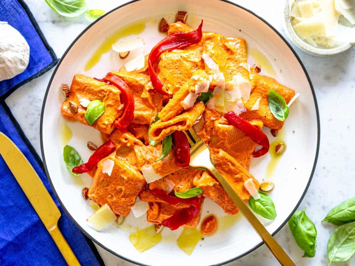 red pepper pasta on a white plate with a black rim