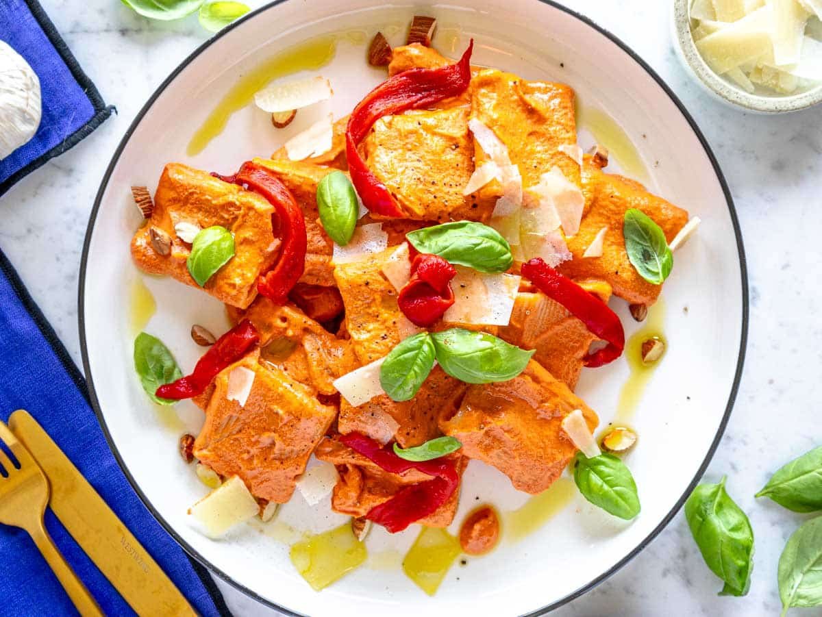 roasted red pepper pasta garnished with bell pepper strips, parmesan, basil, and almonds