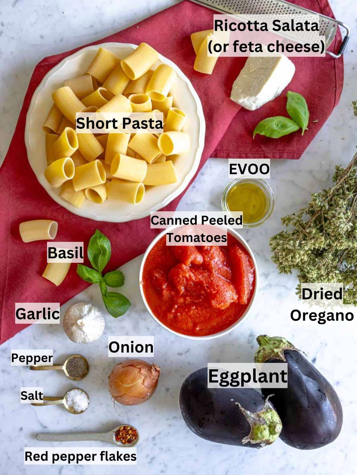 Simple ingredients for pasta alla Norma including eggplant tomatoes basil and ricotta salata.