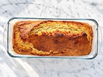 Step 4 Golden vegan banana bread cooling in a parchment-lined loaf pan.