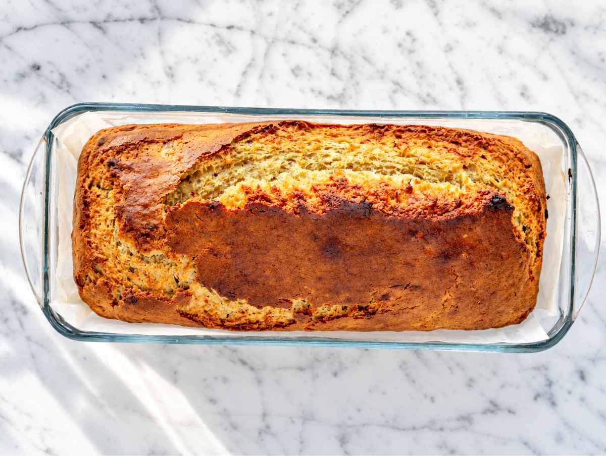 Step 4 Golden vegan banana bread cooling in a parchment-lined loaf pan.