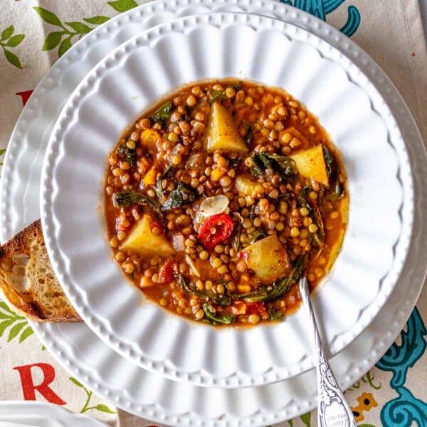 easy lentil soup in a white bowl with bread and a spoon