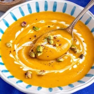 Butternut squash soup with toasted nuts and a rustic spoon.