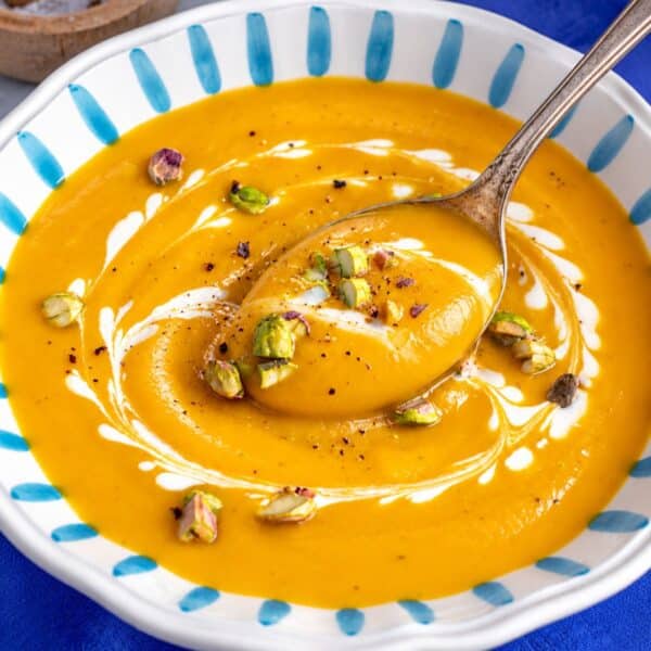 Butternut squash soup with toasted nuts and a rustic spoon.
