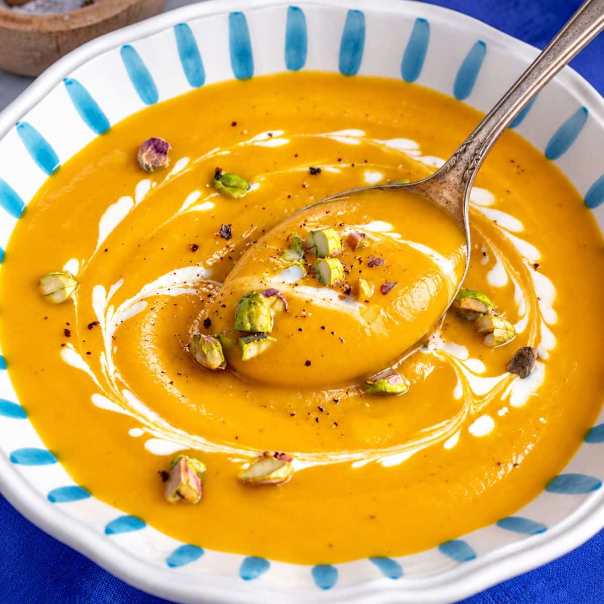 Butternut squash soup with toasted nuts and a rustic spoon.