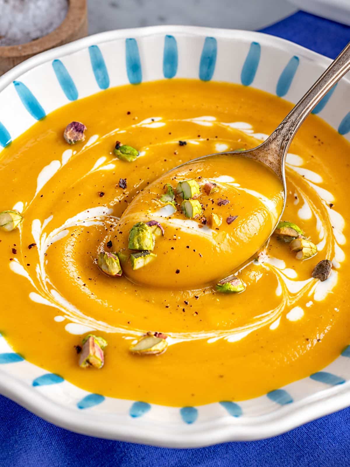Close-up of silky orange soup with a glossy coconut swirl.