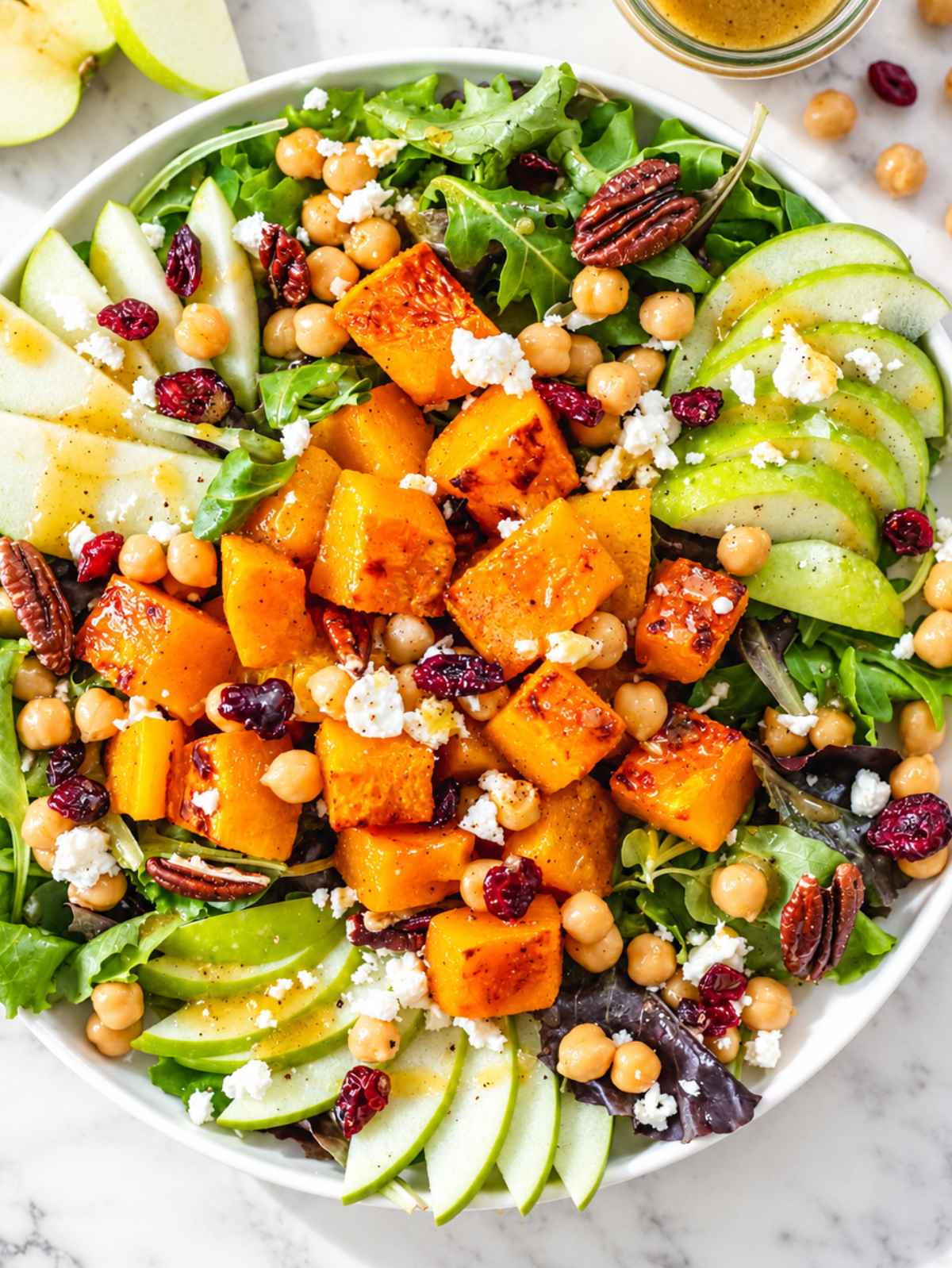 Flat lay of roasted squash, glossy chickpeas, apple, feta, and greens.