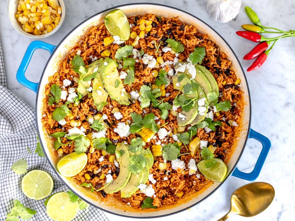 Mexican rice in a blue skillet with corn and avocado