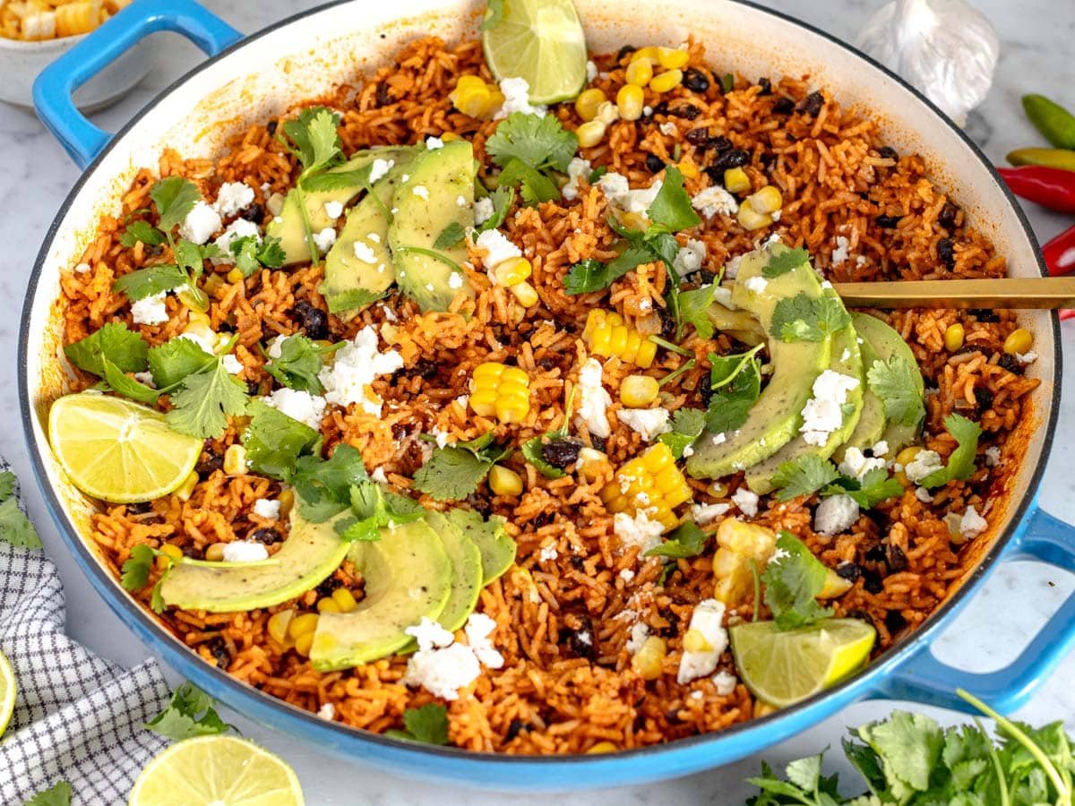 Mexican rice in a blue skillet with a golden spoon