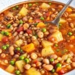 Rustic barley soup with beans and potatoes served in natural window light.