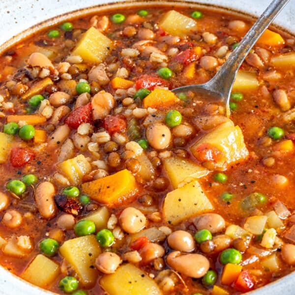 Rustic barley soup with beans and potatoes served in natural window light.