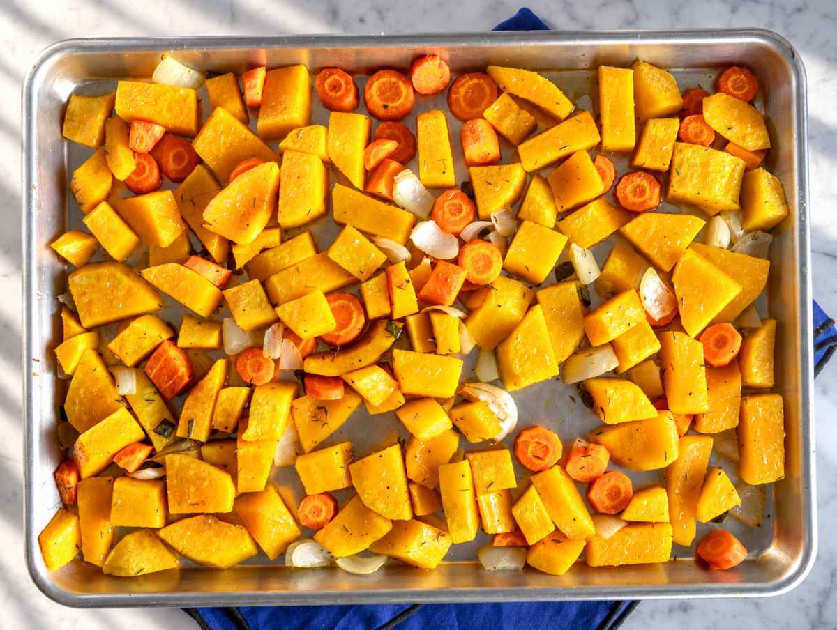 Step 1 Squash, carrots, onion, garlic, and herbs spread across a baking sheet.