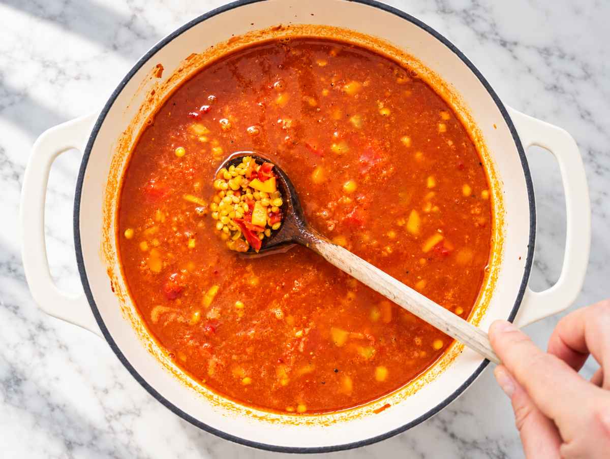 Step 2 Lentils simmering with vegetables and crushed tomatoes in seasoned broth.