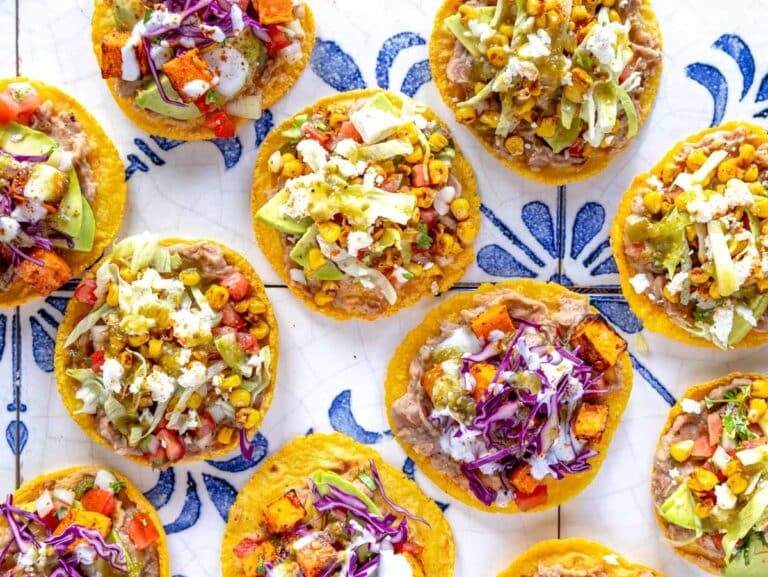 colorful corn tostadas topped with refried beans, vegetables and cheese.