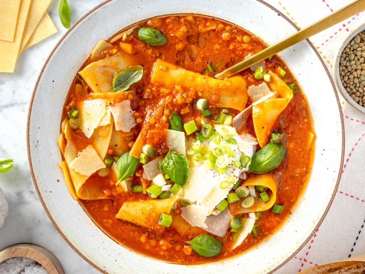 lasagna soup in a bowl topped with ricotta, parmesan, and basil