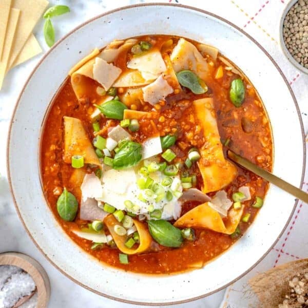 lasagna soup with ricotta, basil leaves, and a golden spoon