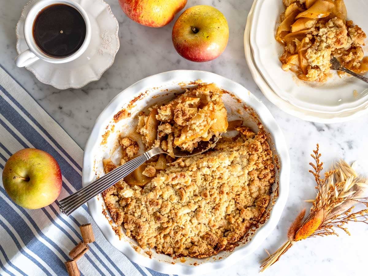 Apple crumble in pie dish and a cup of coffee