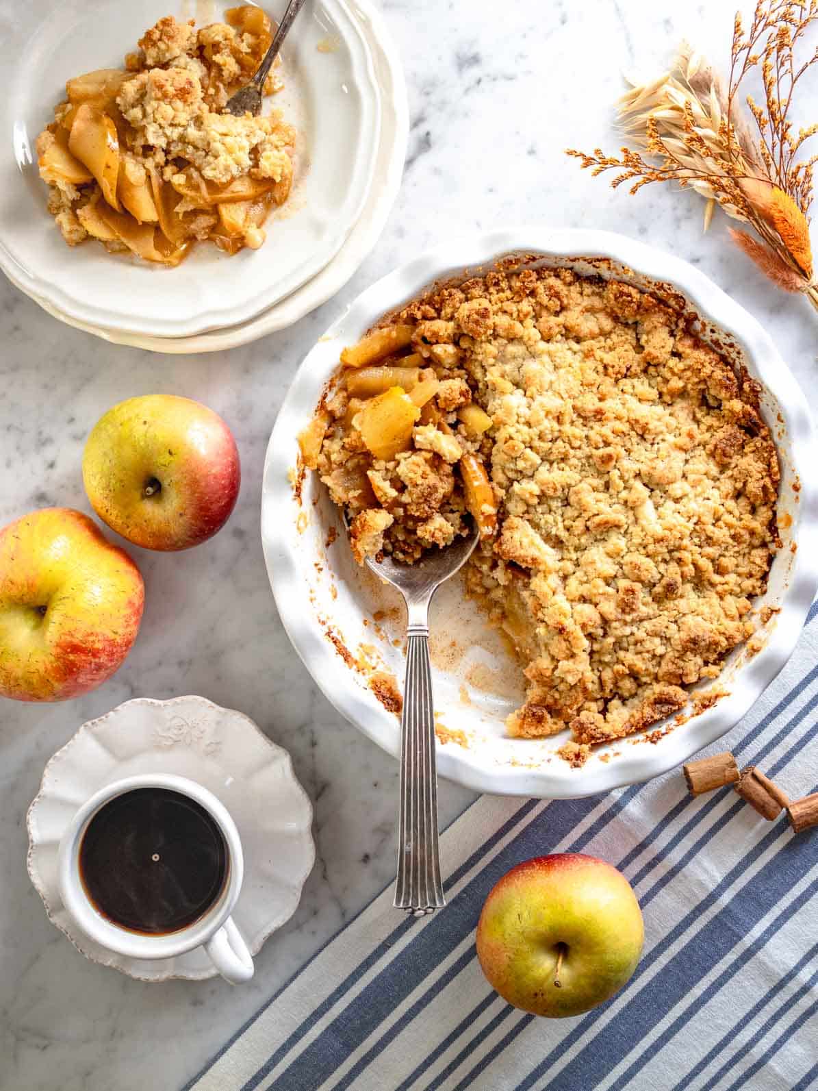 Apple crumble with a silver spoon and a cup of coffee