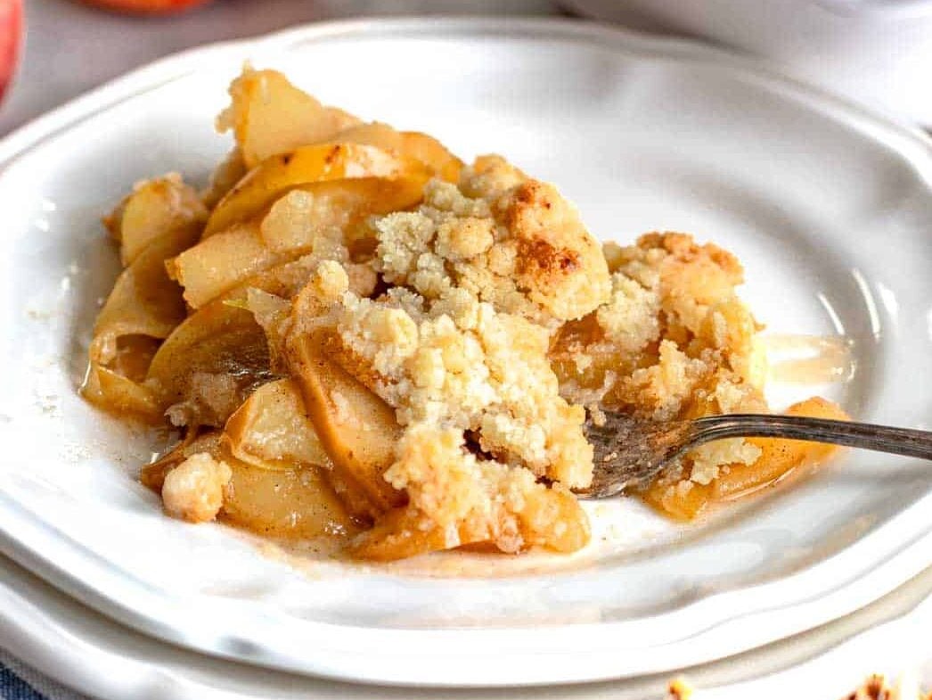 A scooped put portion of apple crumble on a white plate